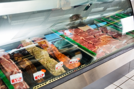 Variety of meat displayed in glass cabinet at butcher's shopの写真素材