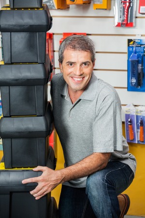 Man Lifting Stacked Toolboxes In Hardware Shopの写真素材