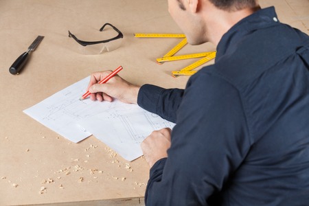 Architect Drawing Diagram At Table In Workshopの写真素材