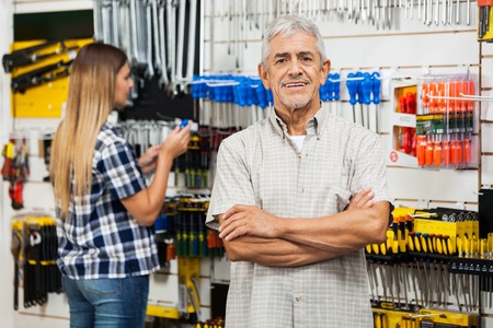Confident Senior Man With Arms Crossed In Hardware Storeの写真素材