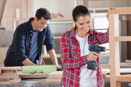 Happy Carpenter Drilling Wood In Workshopの写真素材