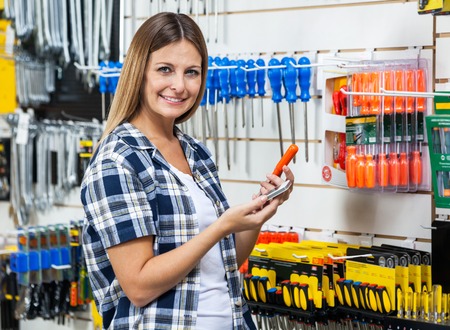 Customer Holding Cellphone And Screwdriver In Storeの写真素材