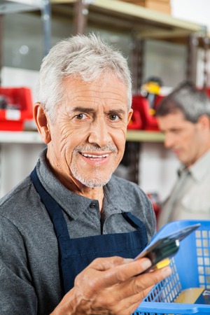 Confident Senior Salesman Holding Tool In Storeの写真素材