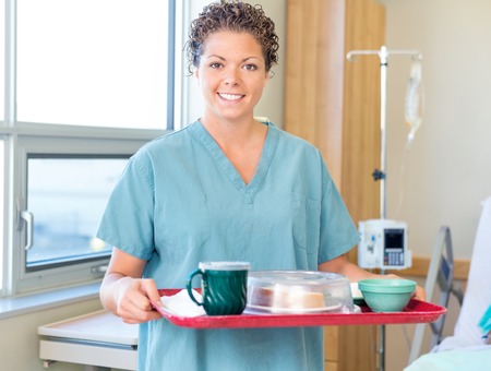 Nurse Holding Breakfast Tray In Hospital Roomの写真素材