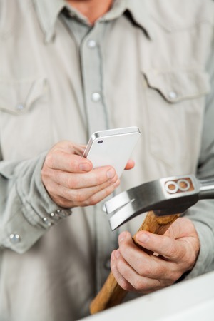 Man Scanning Hammer Through Smartphoneの写真素材