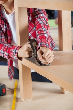 Carpenter Using Planer On Wooden Shelfの写真素材