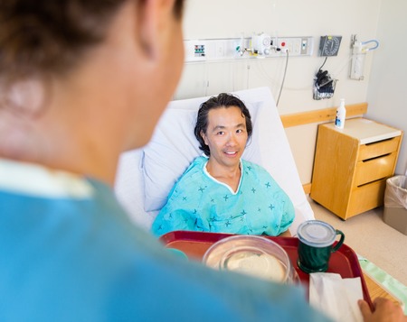 Patient Looking At Nurse Serving Breakfast In Hospitalの写真素材
