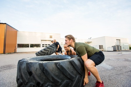 Fit Athletes Doing Tire-Flip Exerciseの写真素材