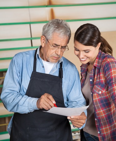 Carpenters Over Document In Workshop