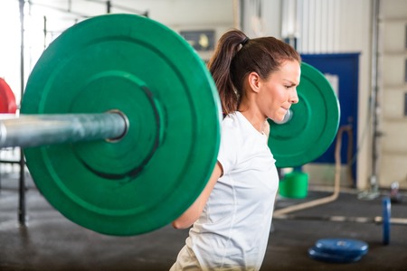 Fit Woman Lifting Barbell in Gymの写真素材