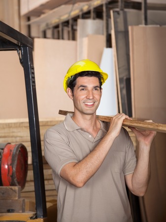 Carpenter Carrying Plank While Looking Awayの写真素材