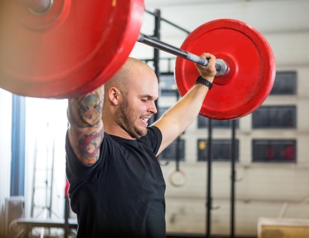 Athlete Exercising With Barbell At Gymの写真素材