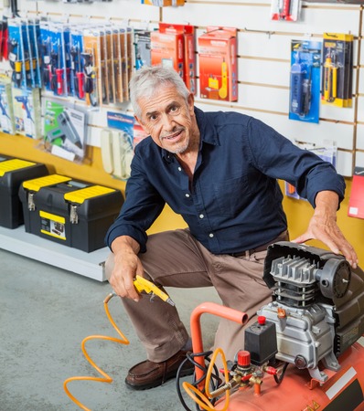 Confident Senior Man With Air Compressor In Storeの写真素材