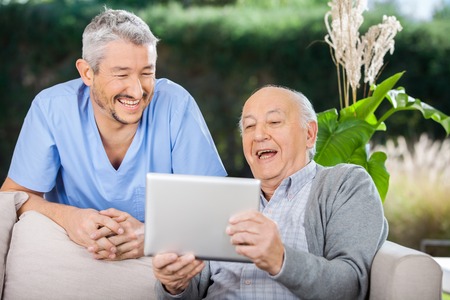 Male Caretaker And Senior Man Using Tablet PCの写真素材