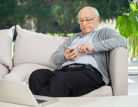 Senior Man Text Messaging Through Smartphone At Porchの写真素材