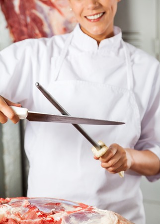 Midsection Of Female Butcher Sharpening Knifeの写真素材