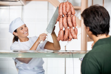 Butcher Selling Sausages To Male Customerの写真素材