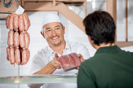 Butcher Showing Packed Sausages To Customerの写真素材