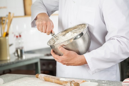 Chef Mixing Batter With Wire Whisk In Bowl In Kitchenの写真素材