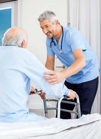 Caretaker Assisting Senior Man To Use Walking Frameの写真素材