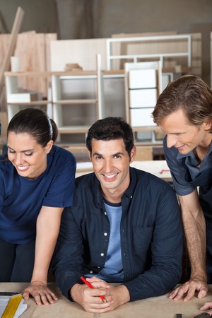 Confident Carpenter With Team At Tableの写真素材