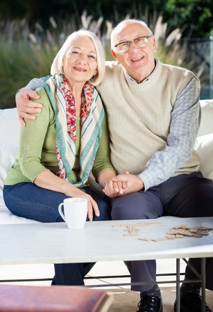 Senior Man Sitting With Arm Around Woman On Couchの写真素材