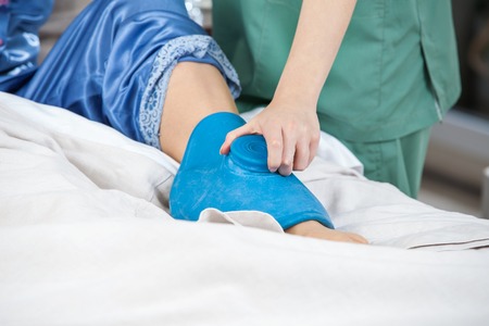 Caretaker Using Hot Water Bag On Senior Womans Legの写真素材