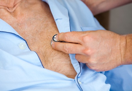 Caretaker Examining Senior Mans Chest With Stethoscope