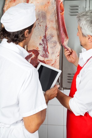 Butchers Analyzing Meat Hanging In Butcheryの写真素材