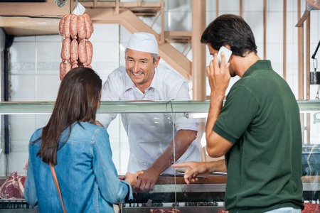 Butcher Selling Meat To Couple In Butcheryの写真素材
