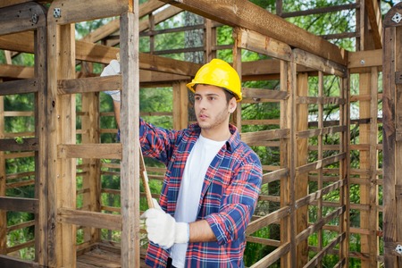 Worker Taking Measurements In Wooden Cabinの写真素材