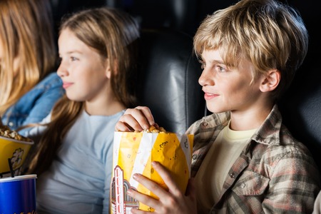 Boy Eating Popcorn While Watching Movie With Familyの写真素材
