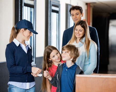 Worker Checking Tickets Of Family At Cinemaの写真素材