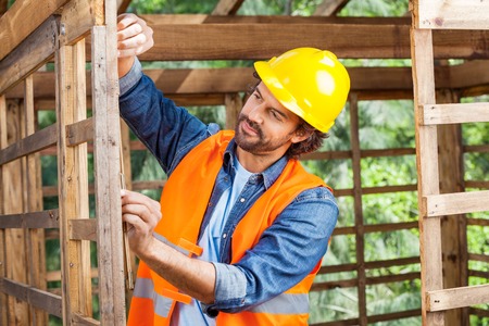 Construction Worker Measuring Timber Frame