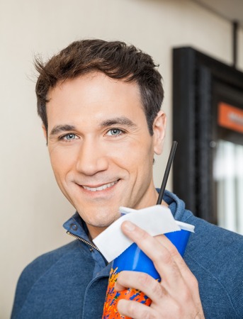 Happy Man Holding Drink And Ticket At Cinemaの写真素材