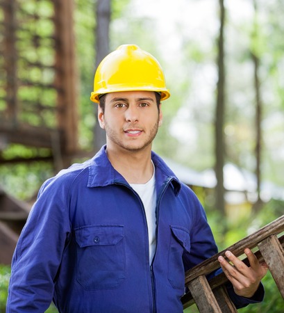 Confident Worker Carrying Ladder At Construction Site