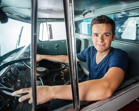 Portrait of confident male firefighter driving firetruckの写真素材