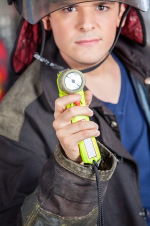 Portrait of confident young male fireman holding torch at fire stationの写真素材