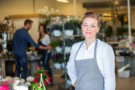 Portrait of confident mid adult female salesperson at flower shopの写真素材