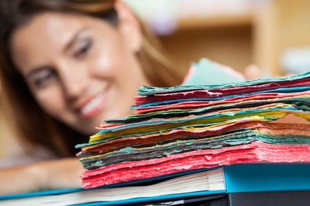 Closeup of multi colored papers with saleswoman smiling in background at shopの写真素材