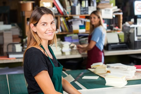 Portrait of smiling mid adult female worker standing in paper factory