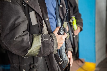 Midsection of fireman holding walkie talkie at fire stationの写真素材