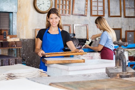 Portrait of smiling female workers making papers in factoryの写真素材
