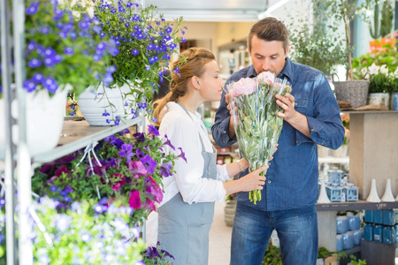 Florist and male customer smelling flower bouquet at storeの写真素材