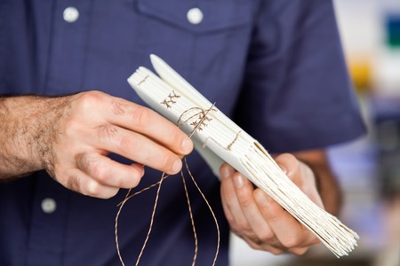 Midsection of male worker binding pages in paper factoryの写真素材