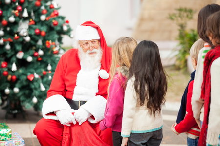Santa Claus looking at children standing in a queue outdoorsの写真素材