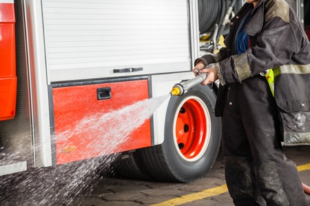 Midsection of firewoman spraying water during training at fire station