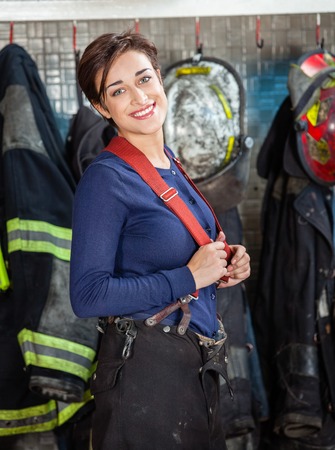 Portrait of happy young firewoman standing at fire stationの写真素材