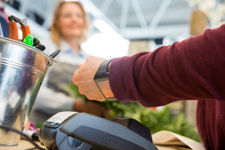 Cropped image of female customer paying through smart watch at flower shopの写真素材