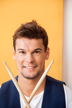 Portrait of confident young man with drumsticks in recording studioの写真素材